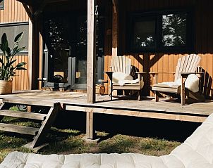 Porch with wooden chairs at Holiday Home in Rutten, Eastern Flevoland, surrounded by nature and tranquility.