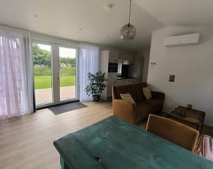 Spacious living room in vacation home FL088, Kraggenburg, with modern furnishings and views of green garden in Eastern Flevoland, Flevoland.