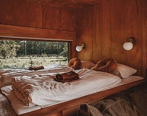 Sfeervolle slaapkamer in Vakantiehuis in Zeewolde, Zuidelijk Flevoland met groot raam en uitzicht op het groen.