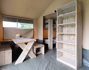 Interieur van Glampingtent de Meeuw in Zeewolde, Flevoland met houten eettafel en stapelbedden, ideaal voor een comfortabele glampingervaring.