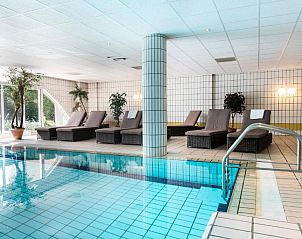 Binnenzwembad met ligstoelen in WestCord Hotel Schylge, West-Terschelling voor ontspanning.