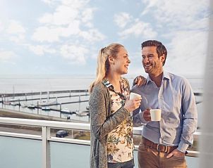 Koppel geniet van koffie op het balkon van WestCord Hotel Schylge, West-Terschelling met uitzicht op de zee.
