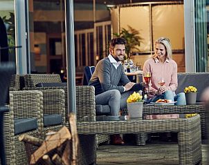 Koppel geniet van een drankje op het terras van WestCord ApartHotel Boschrijck, West-Terschelling.