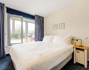 Lichte slaapkamer met comfortabel bed in WestCord ApartHotel Boschrijck, West-Terschelling.