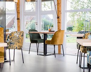 Stijlvolle eetkamer in Hotel Bornholm, West-Terschelling, met kleurrijke stoelen en veel lichtinval.