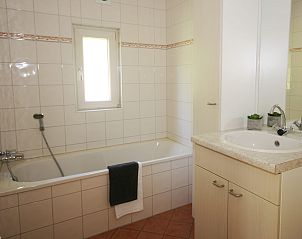 Moderne badkamer in Chalet de Vink, Appelscha, Friesland, met ligbad en wastafel, ideaal voor ontspanning in de Friese bossen.