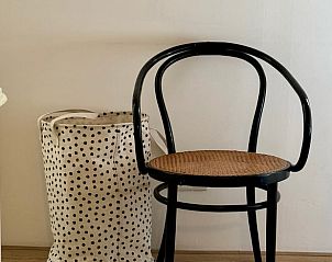 Stijlvolle stoel in Huisje in Appelscha, vakantiehuis in Friesland, naast decoratieve opbergmand.