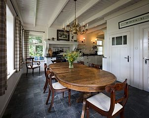 Eetkamer van vakantiehuis in Oldeberkoop, Friesland, met houten tafel en bloemen.