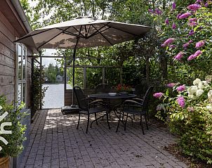 Veranda des Ferienhauses FR270 in Oosterwolde, Friesland, mit Blick auf einen ruhigen See.