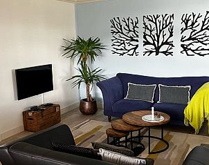 Moderne Sitzecke im Ferienhaus in Oosterwolde mit luxurisem Sofa und Pflanzen.