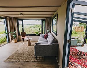 Offenes Wohnzimmer des Ferienhauses in Oosterwolde, mit groen Fenstern und Blick auf die Natur in Friesland.