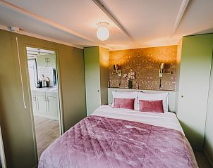 Attraktives Schlafzimmer im Ferienhaus in Oosterwolde, mit warmen Farben und bequemen Betten.