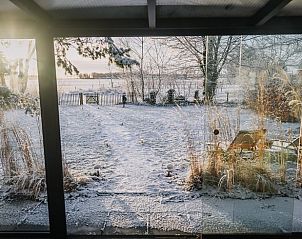 Winterliche Aussicht vom Wintergarten des Ferienhauses in Oosterwolde, mit verschneitem Garten in Friesland.