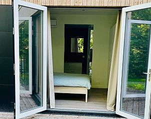 Slaapkamer met openslaande deuren naar de natuur bij Vakantiehuisje in Oosterwolde, Friesland.