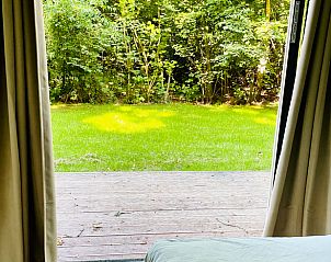 Uitzicht vanuit slaapkamer op groene tuin in Vakantiehuisje in Oosterwolde, Friesland.