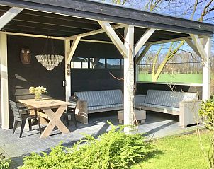 Overdekt terras met zitgelegenheid in Vakantiehuis in Boijl, omgeven door de Friese bossen van Friesland.