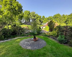 Groene tuin van Vakantiehuis in Boijl met centrale plantenbak en bomen.