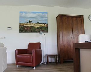 Knusse leeshoek in Huisje in Boijl, vakantiehuis in Friesland, met leunstoel en kunst aan de muur.