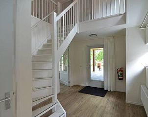 Lichte hal in Huisje in Boijl, vakantiehuis in Friesland, met moderne trap en toegang tot terras.