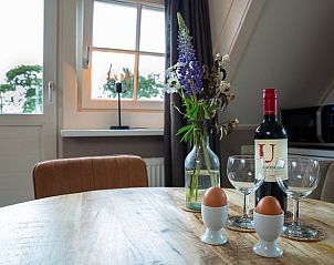 Gezellige eettafel in Vakantiehuis in Hoornsterzwaag, Friesland, met wijn en bloemen.
