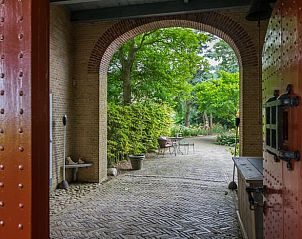 Doorkijk naar de tuin van Huisje in Allingawier met karakteristieke rode deur.