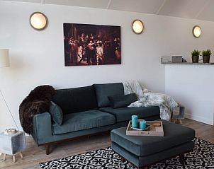 Stijlvolle zithoek in Huisje in Stavoren, Stavoren, met kunst aan de muur en een comfortabele bank.