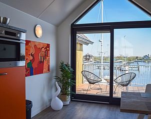 Eetkamer in Huisje in Stavoren, Stavoren, met uitzicht op het water en moderne kunst aan de muur.