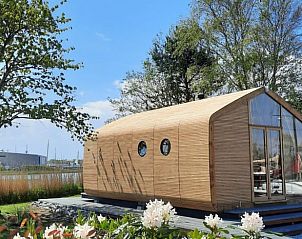 Gezellig houten vakantiehuis, Huisje in Stavoren, omgeven door bomen en bloeiende planten in Friesland.