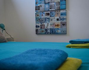 Knusse slaapkamer in Huisje in Stavoren, vakantiehuis in Friesland, met kleurrijke handdoeken en een uitnodigend bed.