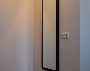 Elegante gang met spiegel in Huisje in Stavoren, een vakantiehuis in Friesland, zorgt voor een ruimtelijk gevoel.