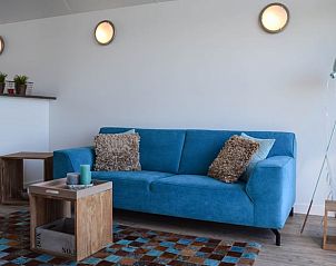 Comfortabele woonkamer in Huisje in Stavoren, een vakantiehuis in Friesland, met een uitnodigende bank en decoratieve accenten.