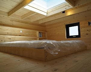 Slaapzolder in Chalet in Hindeloopen, Friesland, met houten afwerking en dakraam voor natuurlijk licht.