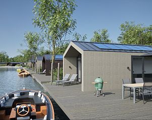 Terras met ligstoelen bij vakantiewoning in Oudehaske, Friesland, aan het water.