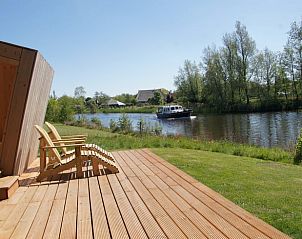 Veranda van vakantiehuisje in Westergeest met uitzicht op het water en groene omgeving.