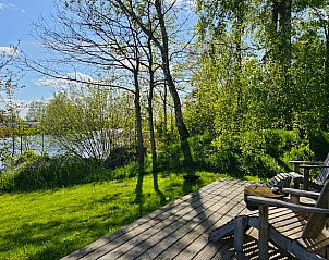 Terras van vakantiehuisje in Westergeest met comfortabele stoelen en uitzicht op de natuur.