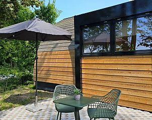 Rustiek terras bij Huisje in Westergeest, Westergeest, met moderne zitplek en parasol.