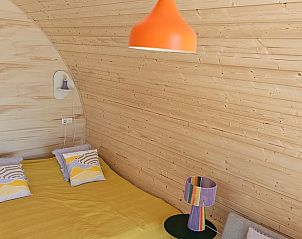 Sfeervolle slaapkamer in Huisje in Westergeest, Friesland, met houten wanden en decoratieve lamp.