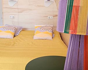 Gezellige inrichting van de slaapkamer in Huisje in Westergeest, met kleurrijke kussens.