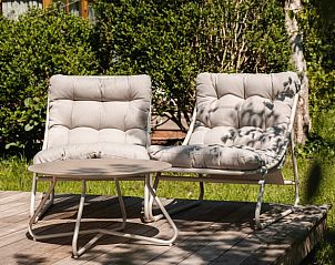 Rustgevend terras met loungestoelen bij Vakantiehuis in Scherpenzeel, omringd door groen op het Friese platteland.