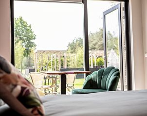 Uitzicht vanuit slaapkamer van Huisje in Blesdijke op terras en groene omgeving.