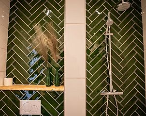 Stijlvolle badkamer van Huisje in Blesdijke met groene tegels en moderne douche.