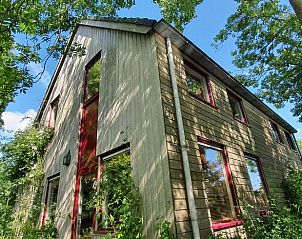 Zijaanzicht van het vakantiehuis Huisje in Easterein, omgeven door groene bomen, op het Friese platteland in Friesland.