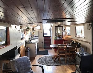 Ruime woonkamer in Huisje in Poppenwier, vakantiehuis in Friesland, met houten interieur en eethoek.