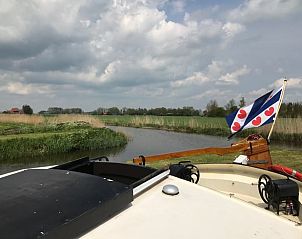 Uitzicht vanaf Huisje in Poppenwier, vakantiehuis in Friesland, met Friese vlag en weids landschap.
