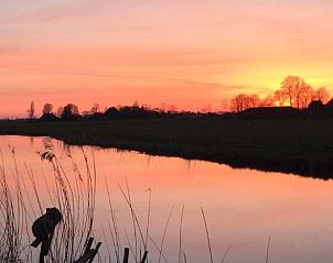 Romantische zonsondergang bij Huisje in Poppenwier, vakantiehuis in Friesland, met reflectie op het water.