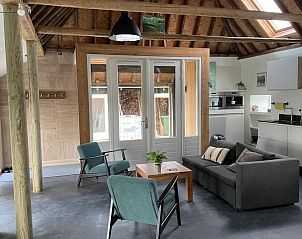 Gezellige zithoek in Huisje in Hallum met veel natuurlijk licht en comfortabele stoelen.