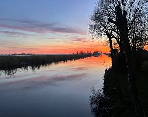 Prachtige zonsondergang bij Huisje in Hallum met reflecties op het water.