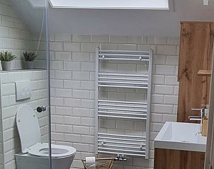 Moderne badkamer in Vakantiehuis in Bantega, Friesland, met strakke witte tegels en houten accenten.