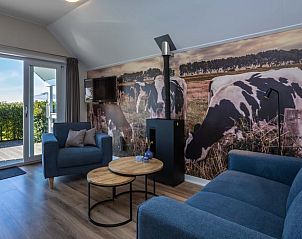 Woonkamer van Huisje in Greonterp met koeienmuurschildering en comfortabele zithoek, Friesland.