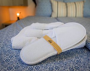 Details van de slaapkamer in Huisje in Greonterp met handdoeken en slippers, Friesland.